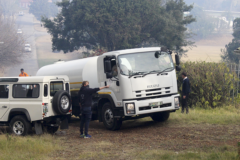 A resident directs the driver of the Rhodes University water tanker to the access point for the veld behind houses under threat.