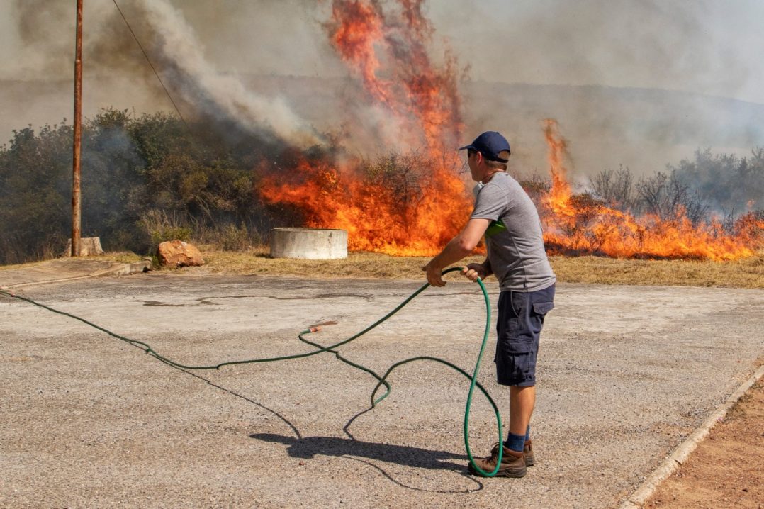 A Hill 60 resident battles flames behind his property during a fire on the western commonage on Thursday 24 September.