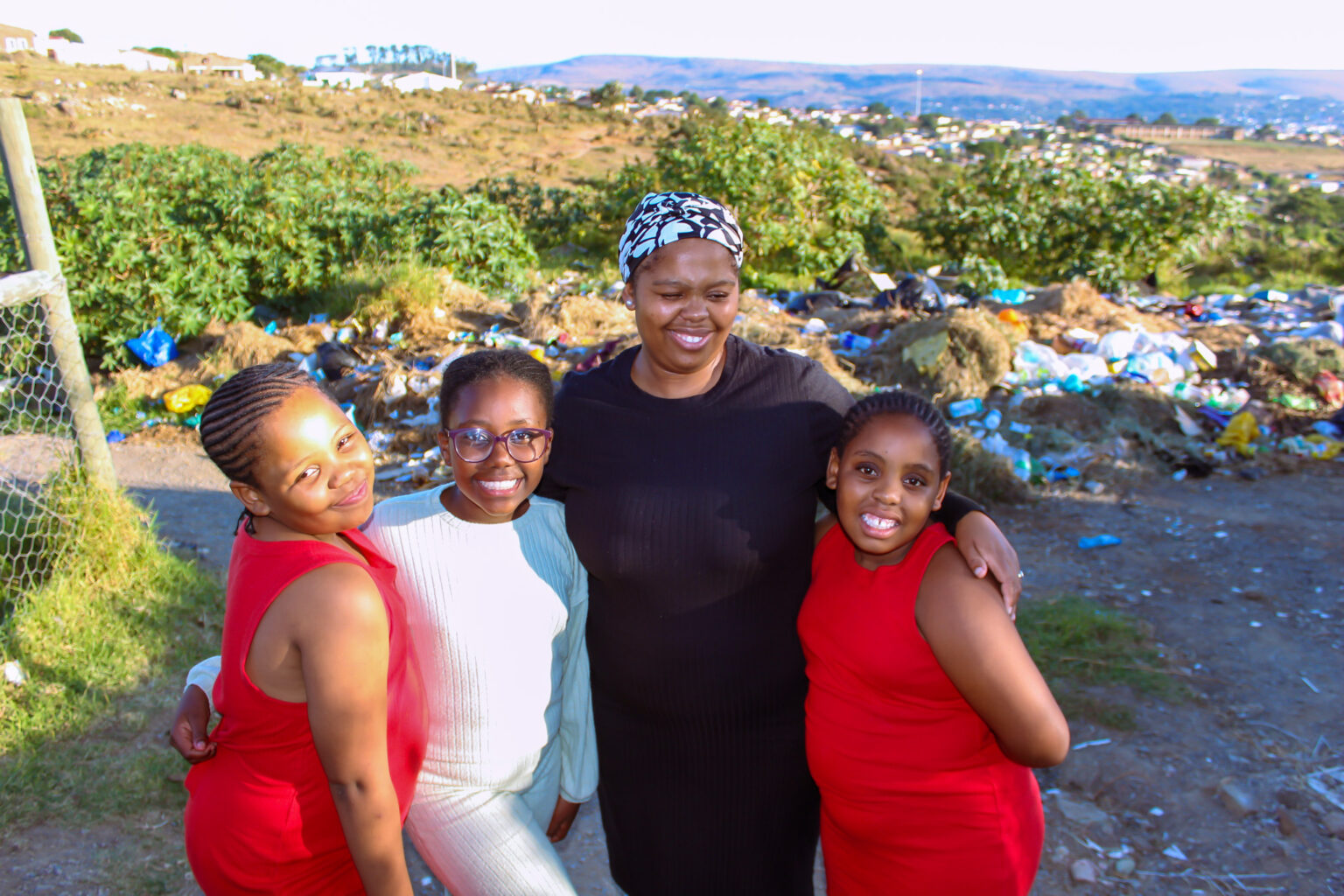 Reseso Libi standing in front of the dumping site right outside her yard with her young daughters. Photo: Buhle Andisiwe Made