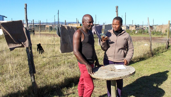 A photo of a Groccotts Mail intern Journalist speaking to a resident of eNkanini.
