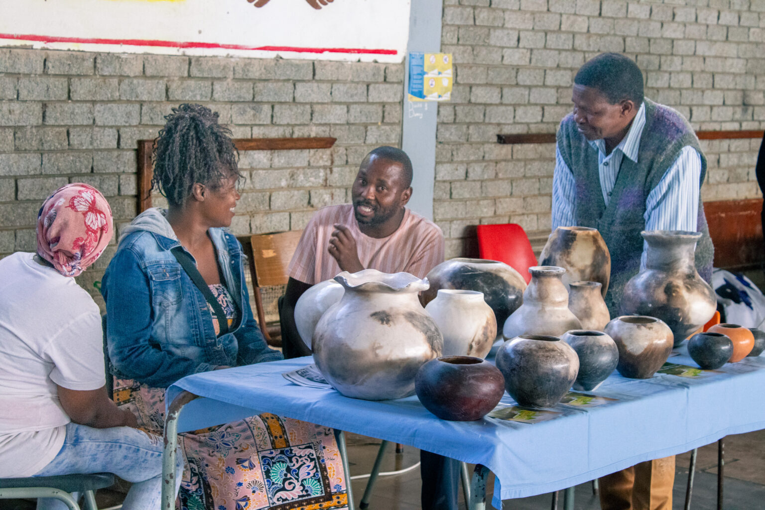 Siyahluma Multi-purpose Production Exhibitors engaging in conversation at their Ngqayi Pottery display table. Photo; Siqhamo Jama.