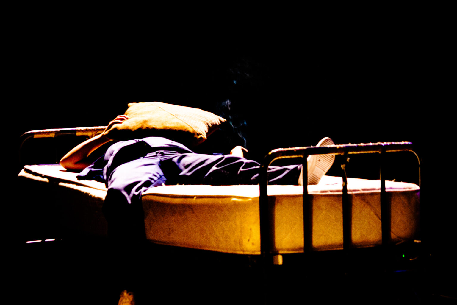 An image of one of the performers exhaustedly laying on a bed During the performance of Womandla. Photo Gavin Gaka