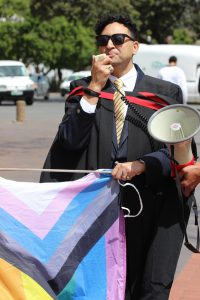 Advocate Shuaib Rahim, Chair of the Pride Week Organising Committee, holds a flag and a megaphone – symbols of the march celebrating Gay Pride. 