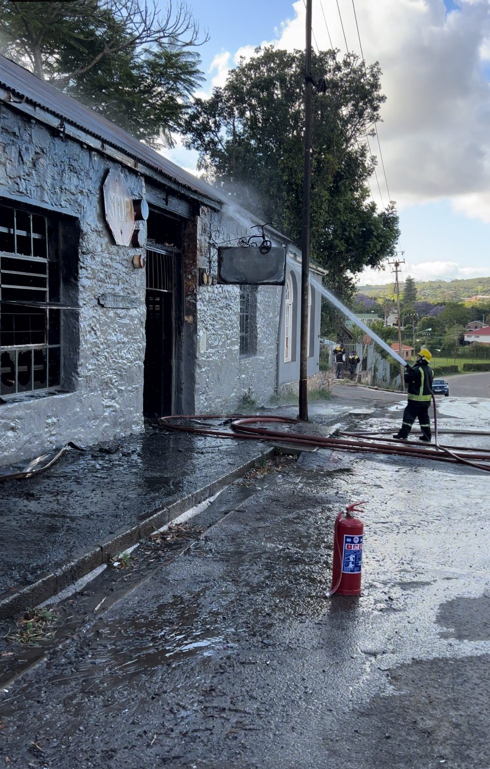 Firefigher sprays Knock Shop roof with water to ensure fire is completely extinguished. Photo: Linda Pona
