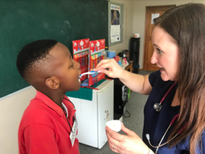 Smile!: Paediatric nurse practitioner Elaina Howell applying a fluoride treatment. Photo: supplied 
