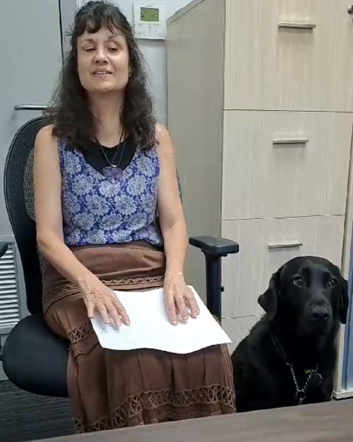 Head Braille and Advisory Standards, Ms Pasha Alden reading an Afrikaans book in Braille format titled "Pragtige Debo" by Beatrice Lalinon Gbado