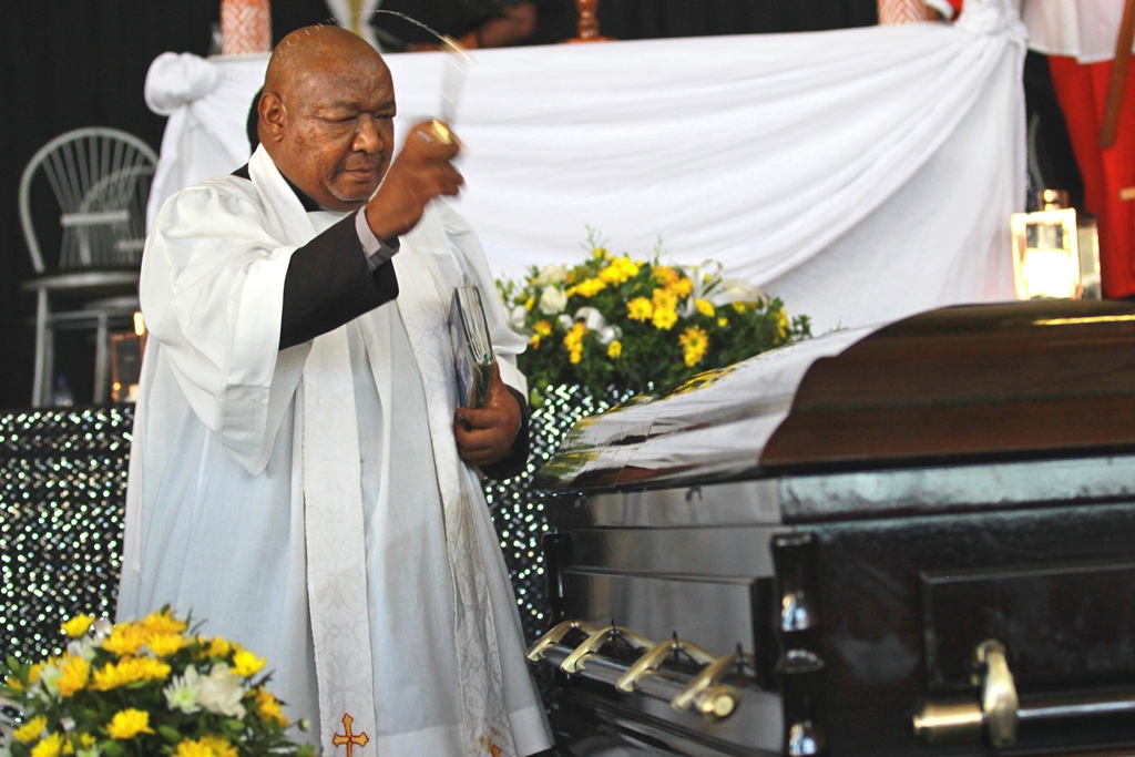 A priest blessing the casket of Ayanda Kota shortly before it was taken to the Waainek Cemetery. Photo: Steven Lang