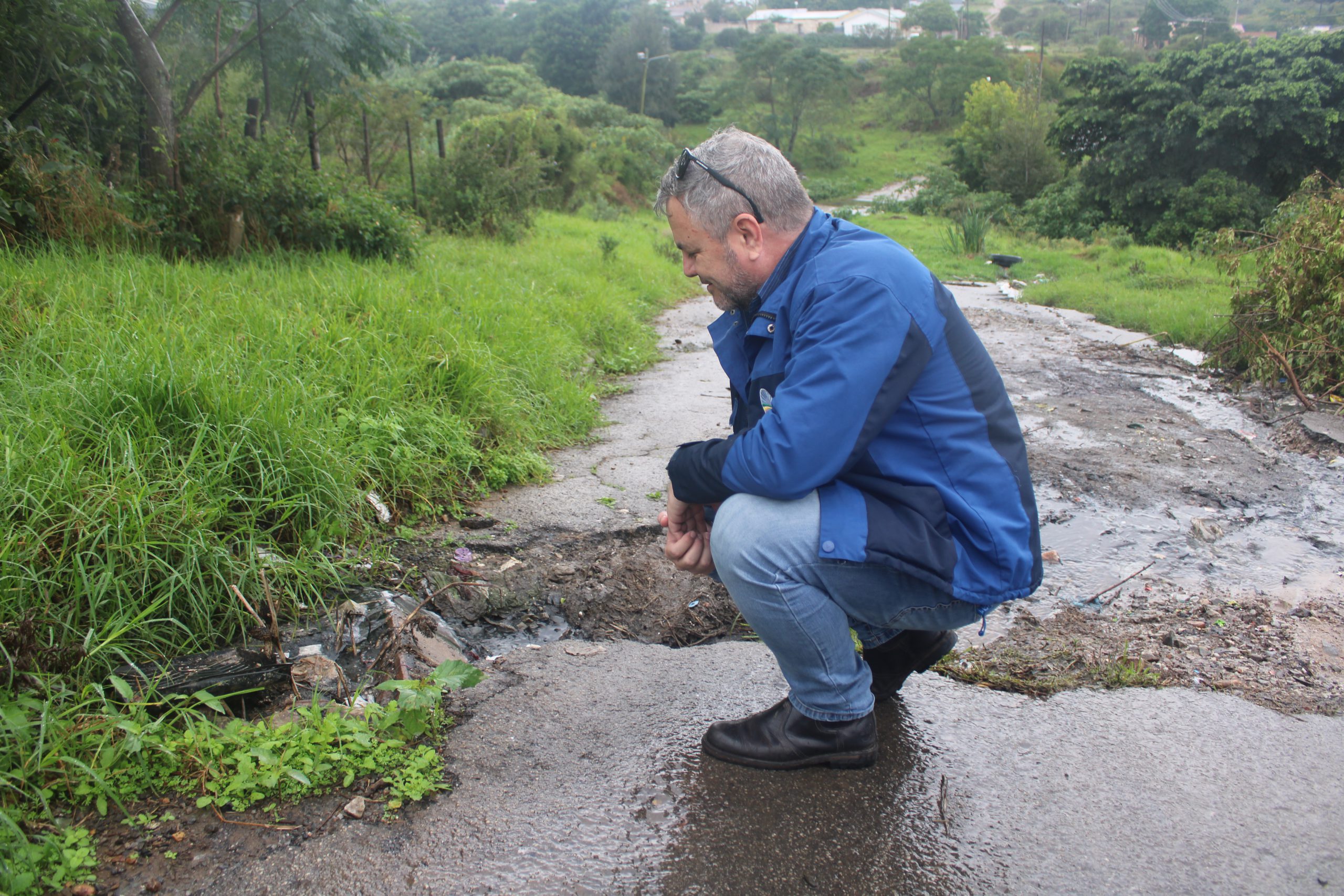 A member of DA inspecting a destroyed road with sewage.
