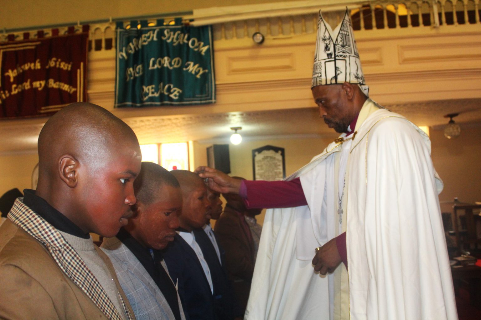 Bishop Siviwe Maqoma of the Anglican Catholic Church, Diocese of Christ the King, anointing and blessing young Makhanda men with Holy Oil at a special service at the Trinity Church building in Hill Street on Sunday. Photo: Luvuyo Mjekula